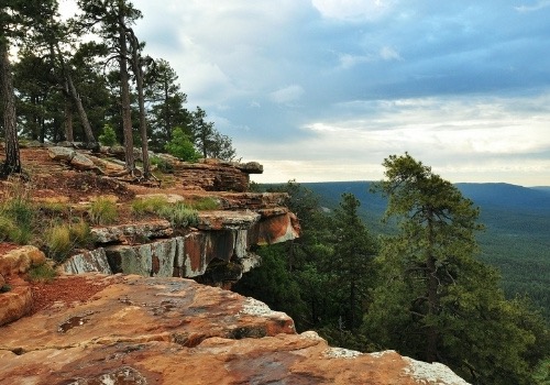 View from atop the Mogollon Rim in Rim Country, Gila County, Arizona — red sandstone ledges and ponderosa pines overlooking the forested valley below.